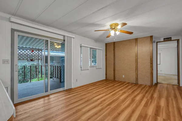 a view of empty room with wooden floor and fan