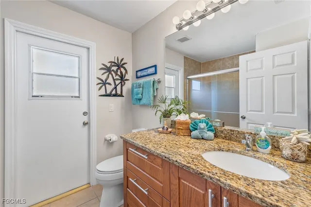 a bathroom with a granite countertop sink a toilet and a mirror