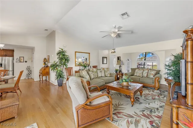 a living room with furniture a chandelier and a dining table with wooden floor