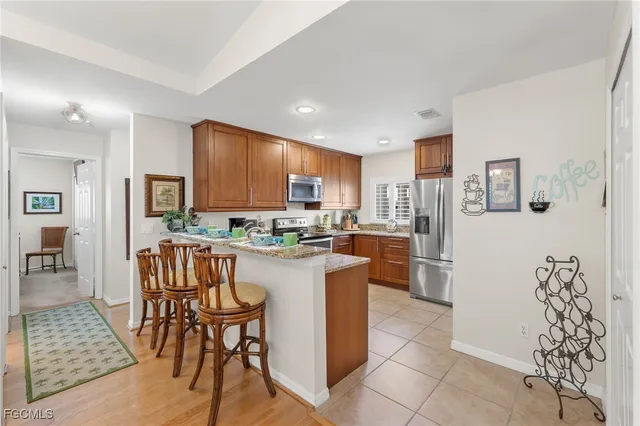 a kitchen with stainless steel appliances granite countertop a refrigerator a stove a sink a dining table and chairs with wooden floor