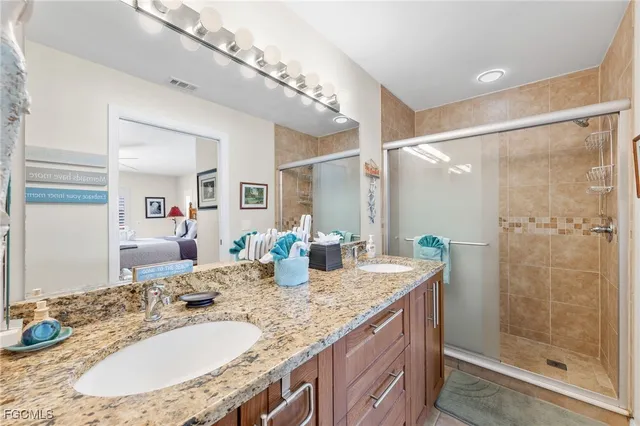 a bathroom with a granite countertop sink a mirror and shower