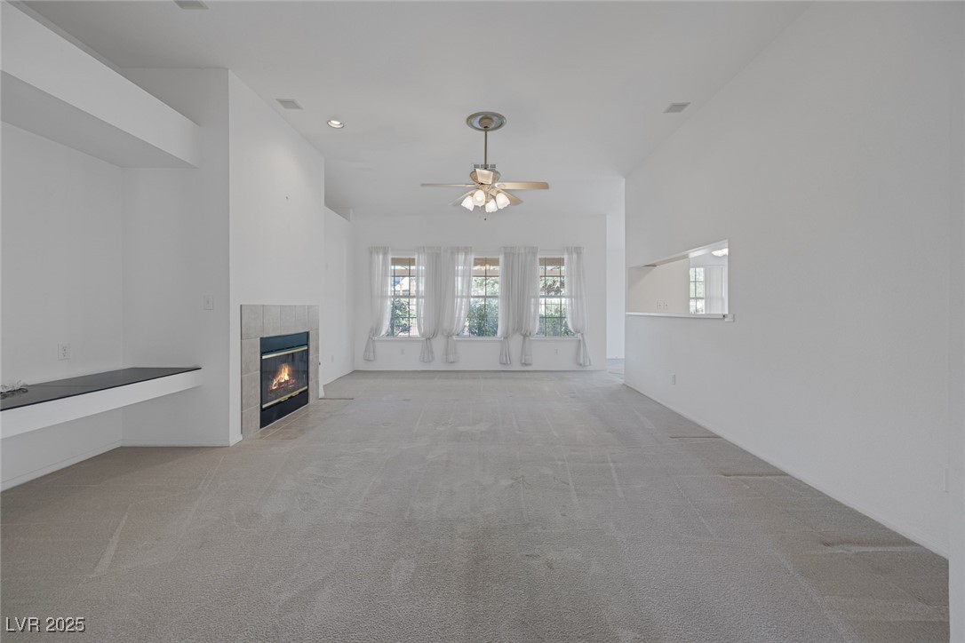 5333 Rim View Lane Las Vegas, NV 89130 - Photo 23 of 55 Unfurnished living room with light carpet, a tile fireplace, ceiling fan, and recessed lighting