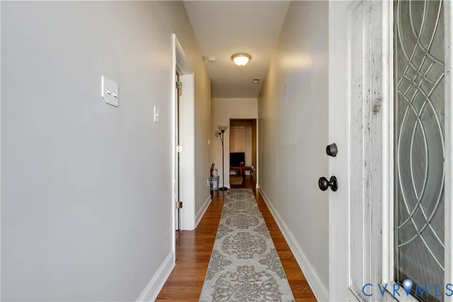 a view of a hallway with wooden floor and a bathroom
