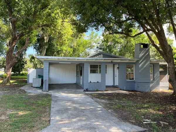 a view of a house with a yard and large tree