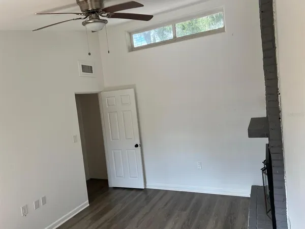 an empty room with wooden floor and fan