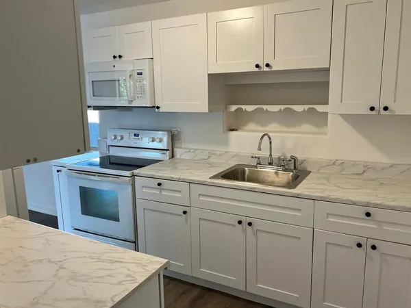 a kitchen with white cabinets and sink