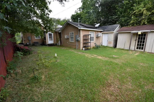 a view of a yard in front of a house with plants and large tree