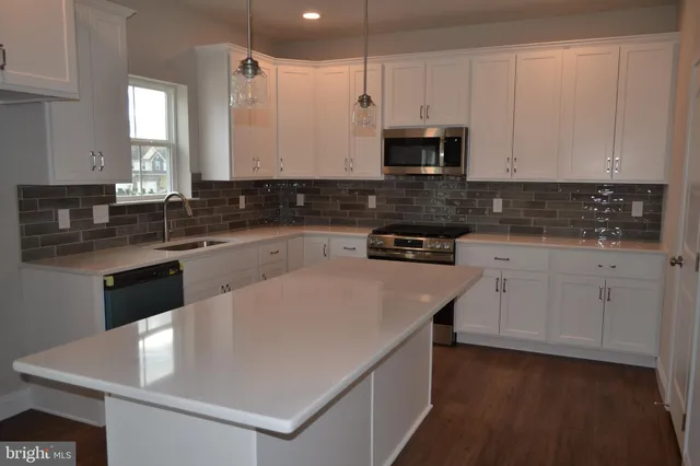 a kitchen with stainless steel appliances granite countertop a sink a stove and white cabinets