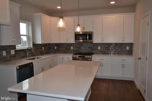 a kitchen with stainless steel appliances a sink a stove a microwave a sink a refrigerator and cabinets