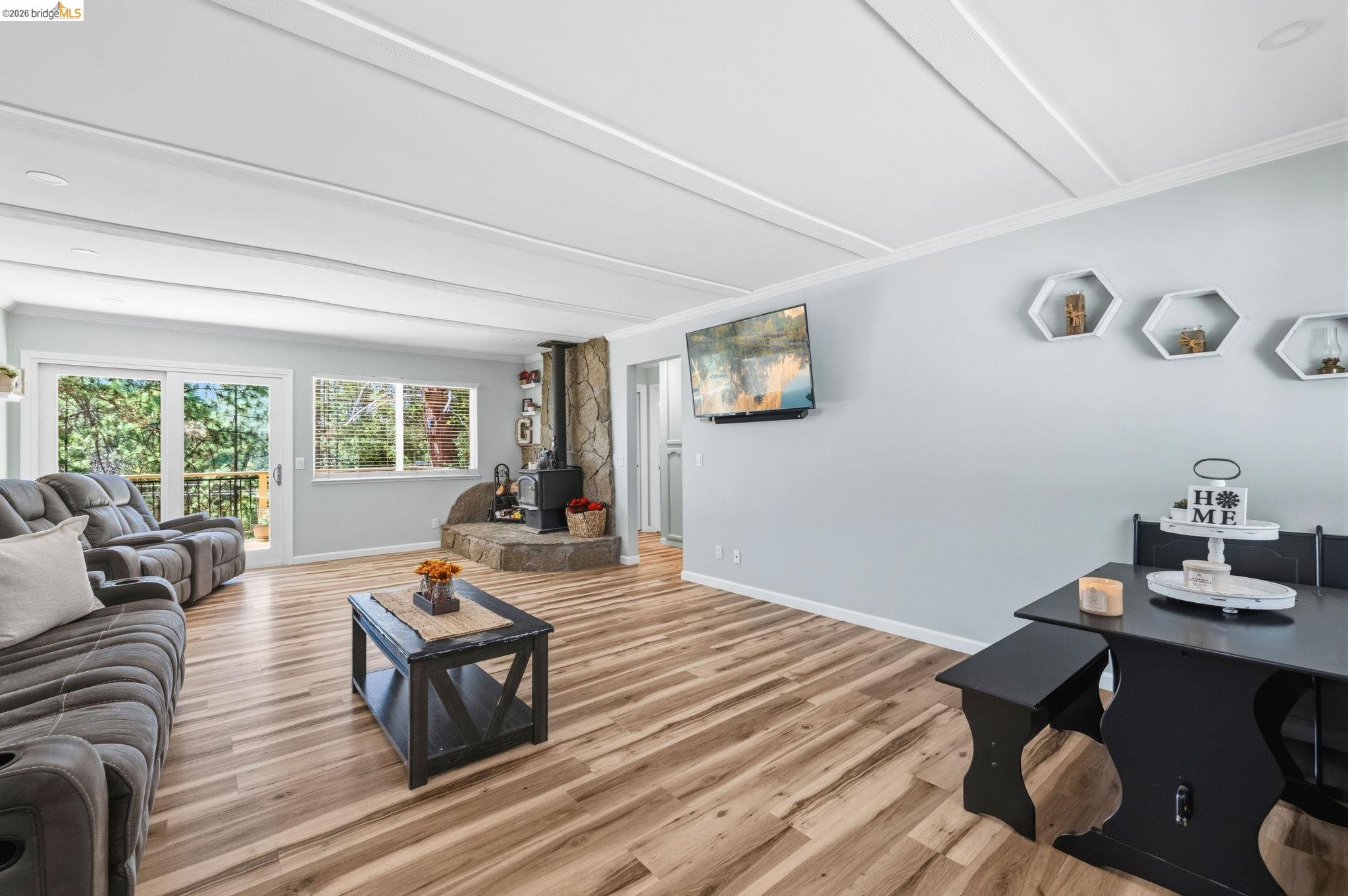 19059 Raboul Court Groveland, CA 95321 - Photo 6 of 21 Living area featuring wood-finish flooring, a stone-surround fireplace with a wood-burning stove, and multiple windows
