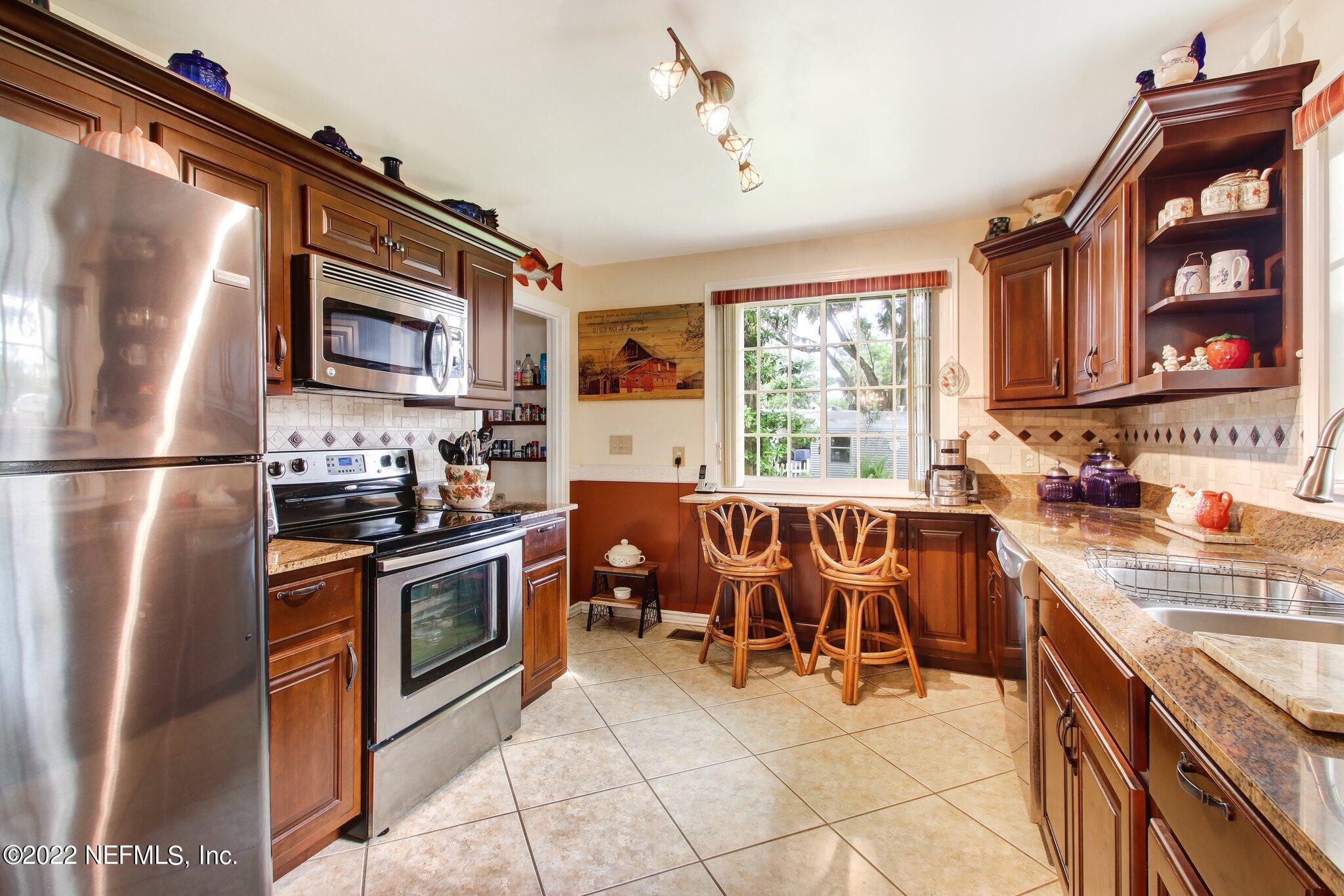 101 Orange Street Satsuma, FL 32189 - Photo 14 of 67 a kitchen with stainless steel appliances granite countertop a stove top oven a sink dishwasher a dining table and chairs with wooden floor