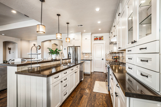 2311 South 1340 West St. George, UT 84770 - Photo 17 of 56 Kitchen with pendant lighting, tasteful backsplash, glass insert cabinets, stainless steel appliances, and white cabinetry