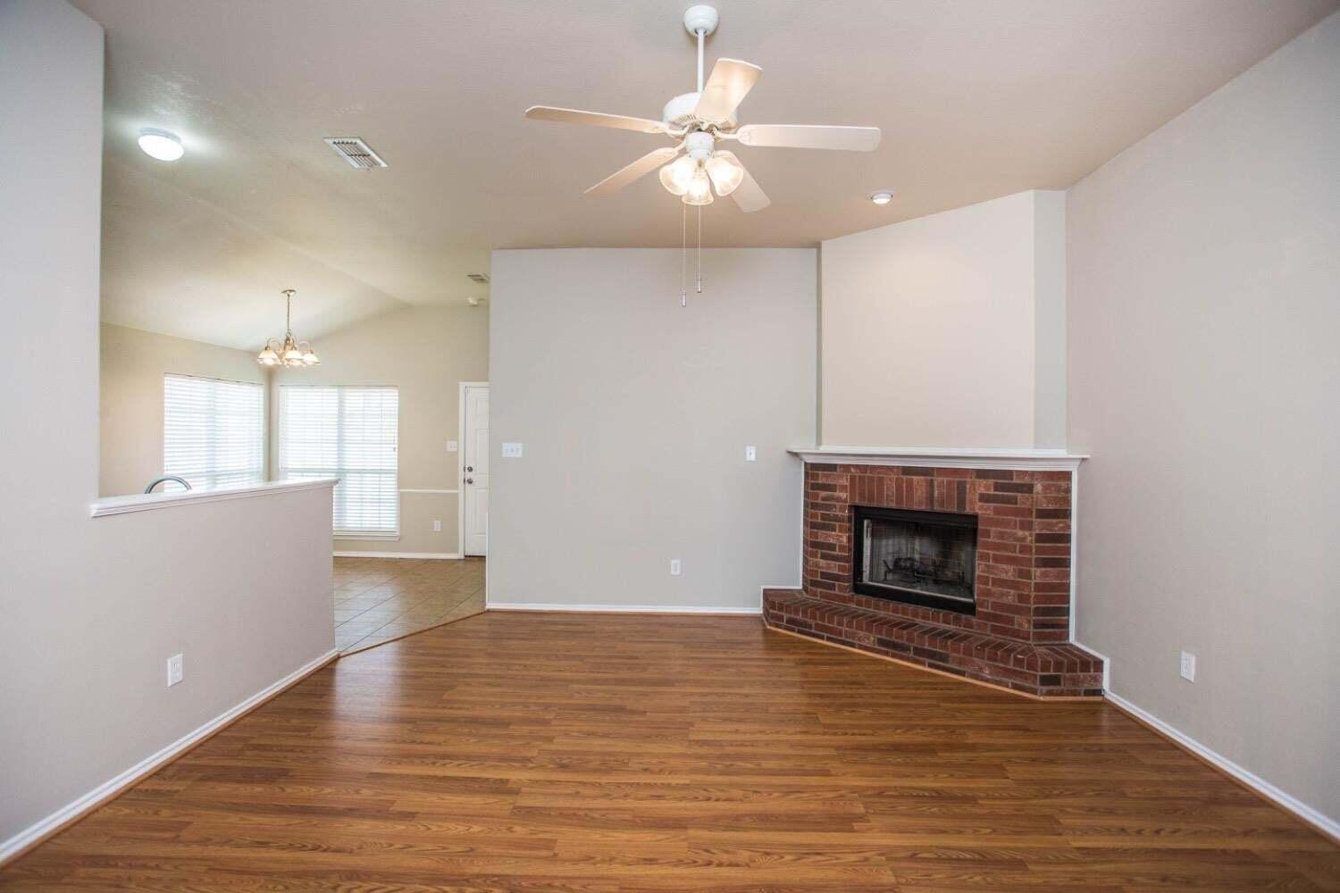 3606 Pontiac Avenue Lubbock, TX 79407 - Photo 2 of 17 an empty room with wooden floor a fireplace a ceiling fan and windows