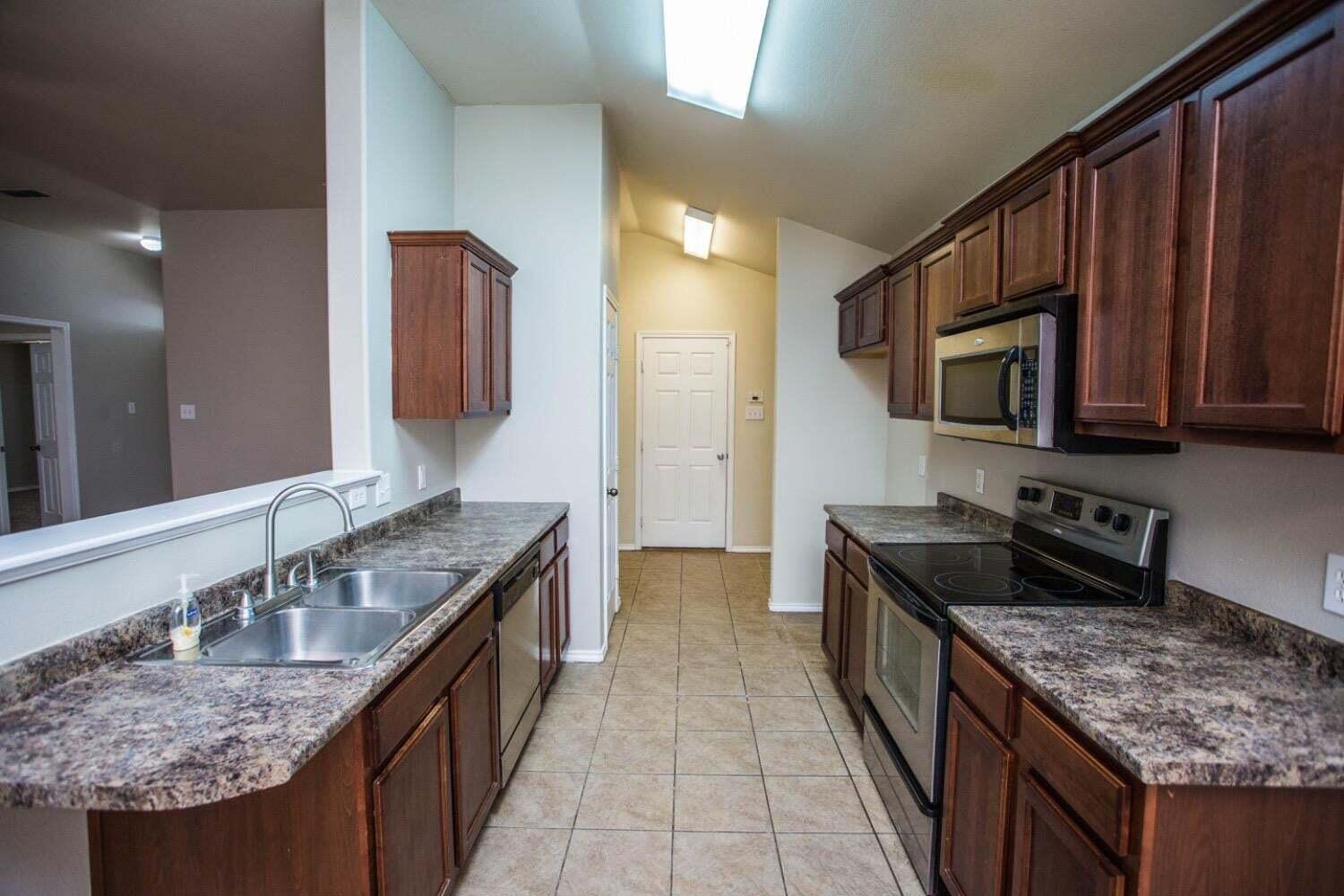 3606 Pontiac Avenue Lubbock, TX 79407 - Photo 6 of 17 a kitchen with granite countertop kitchen island stainless steel appliances a sink stove top oven and microwave