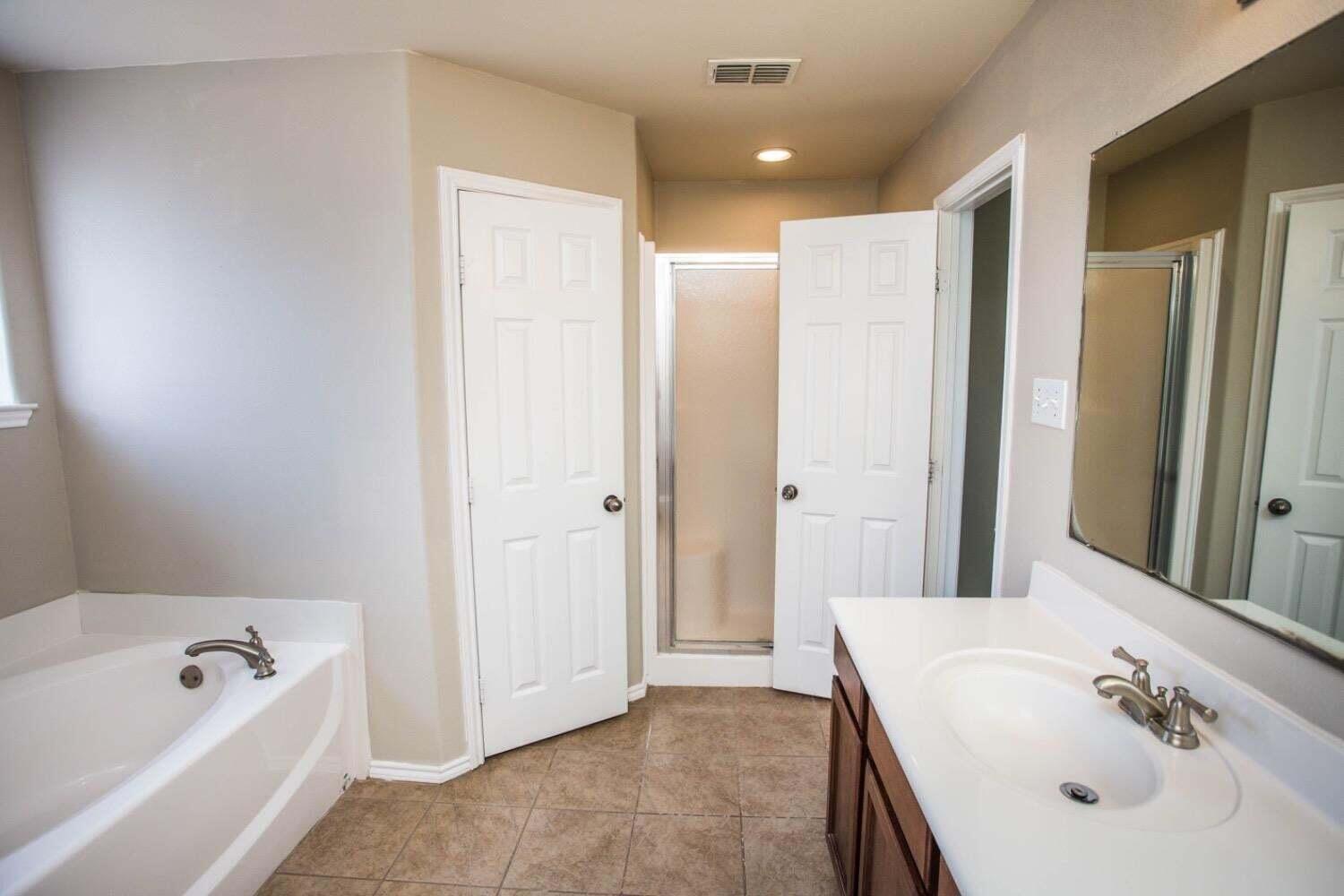 3606 Pontiac Avenue Lubbock, TX 79407 - Photo 10 of 17 a bathroom with a tub sink and mirror
