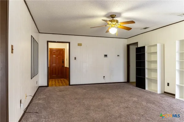 an empty room with closet and a chandelier fan