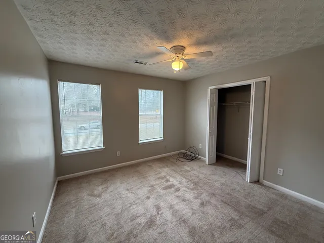 an empty room with windows and fan