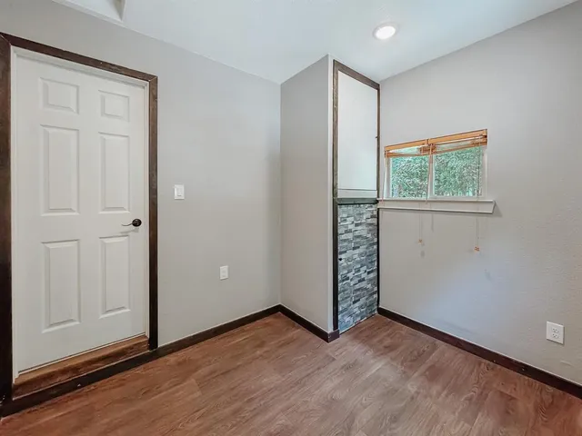 an empty room with wooden floor closet and windows