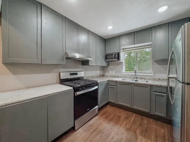 a kitchen with granite countertop stainless steel appliances a stove sink and cabinets