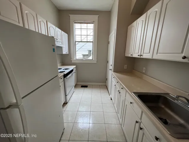 a kitchen with granite countertop white cabinets and white appliances