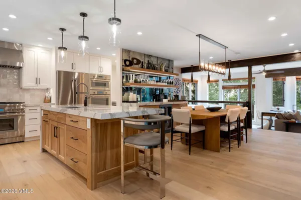 a kitchen with stainless steel appliances kitchen island granite countertop a table chairs and a view of living room