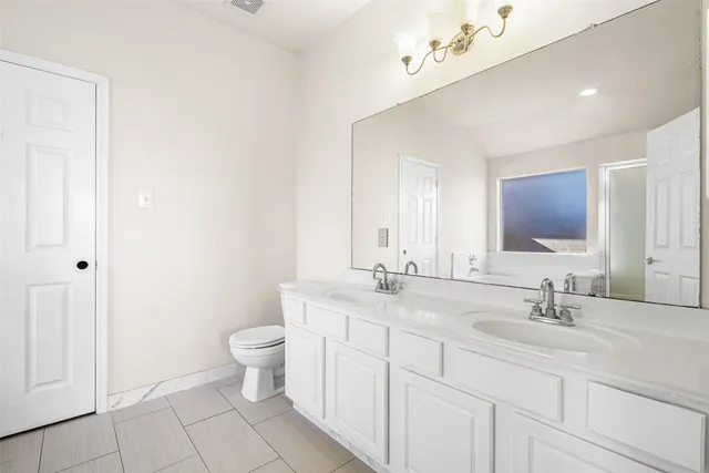 a bathroom with a double vanity sink mirror and toilet