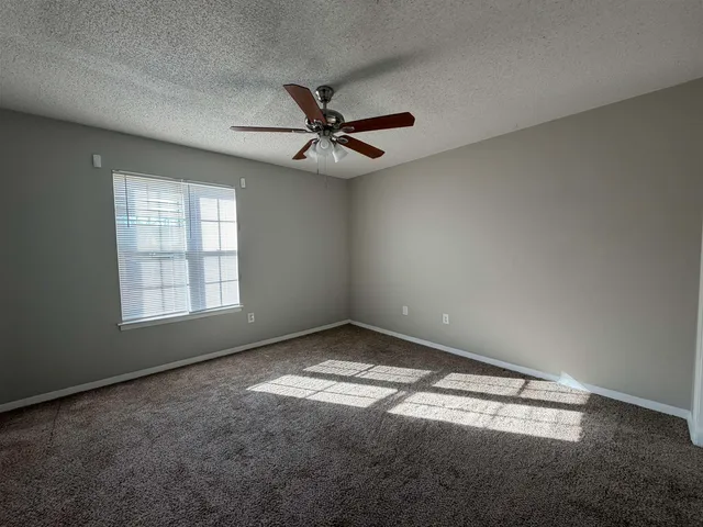 an empty room with a window and a fan