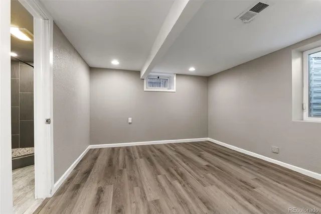 an empty room with wooden floor and windows