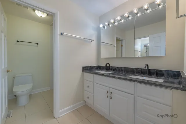 a bathroom with a granite countertop sink a toilet and mirror