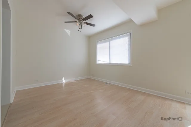 an empty room with a window and a fan