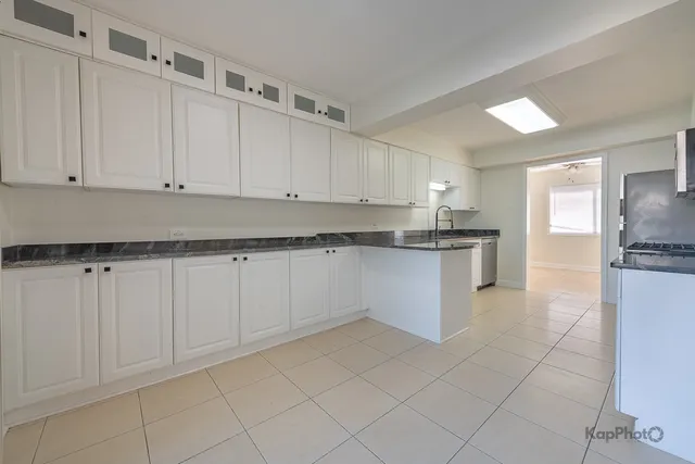 a kitchen with granite countertop white cabinets and stainless steel appliances