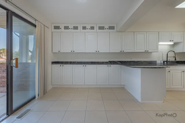 a view of kitchen with granite countertop white cabinets