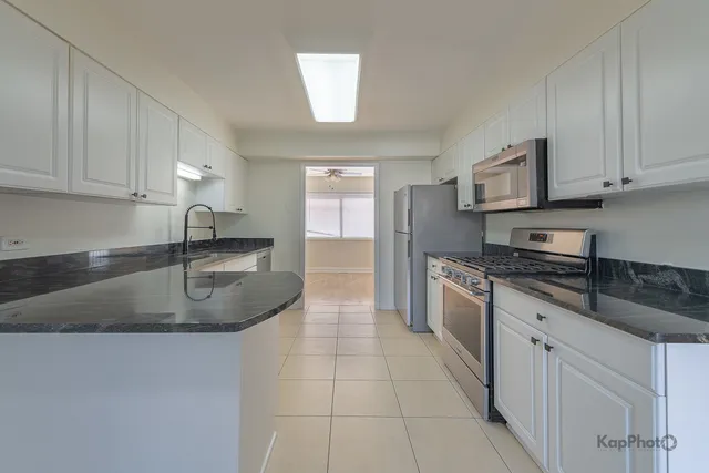a kitchen with stainless steel appliances granite countertop a sink a stove and cabinets