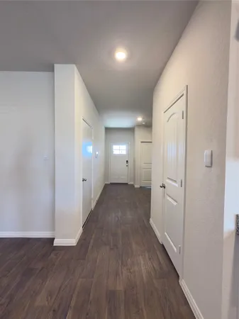 a large white kitchen with kitchen island a sink wooden floor and a refrigerator