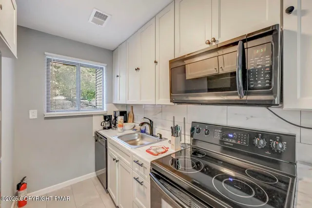 a kitchen with stainless steel appliances granite countertop a stove a sink and a microwave