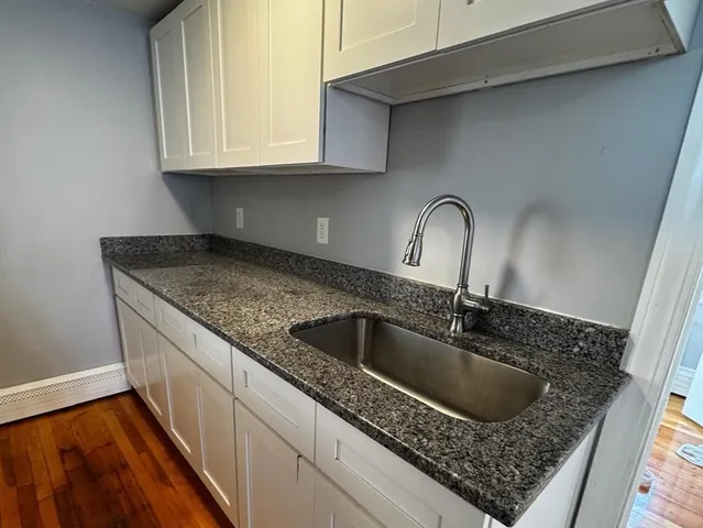 a kitchen with granite countertop a sink a stove and cabinets