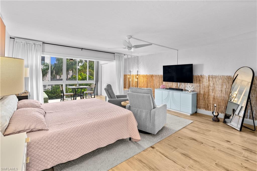 377 Vanderbilt Beach Road, Unit 102 Naples, FL 34108 - Photo 10 of 19 a bedroom with a bed flat screen tv and a large window