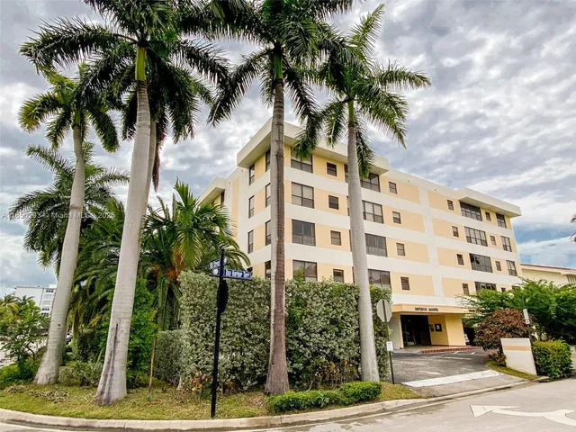 a front view of multi story residential apartment building with yard and sign board
