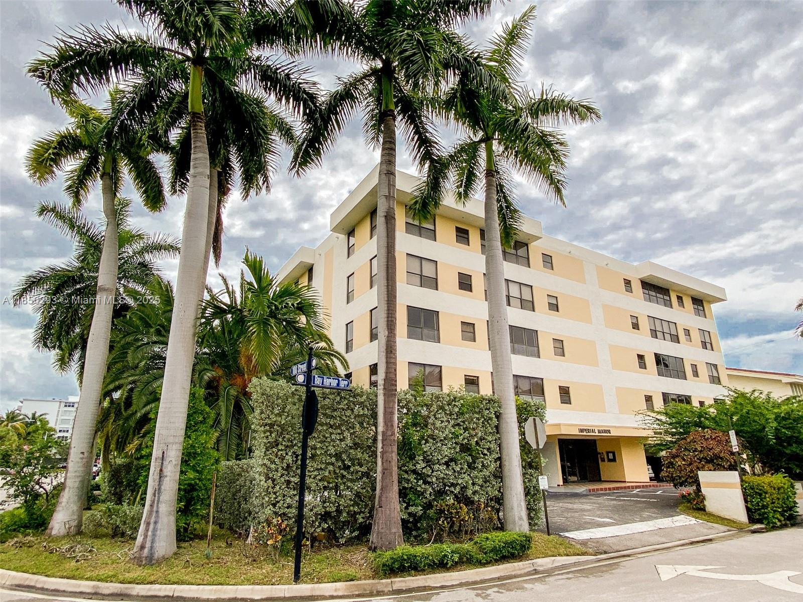 a front view of multi story residential apartment building with yard and sign board