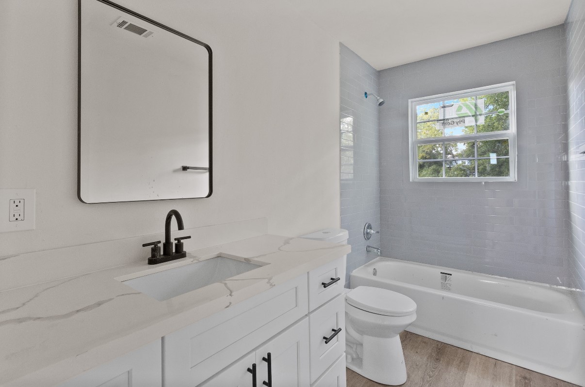 5031 Mallow Street Houston, TX 77033 - Photo 5 of 11 a bathroom with a toilet a sink a mirror and a bathtub
