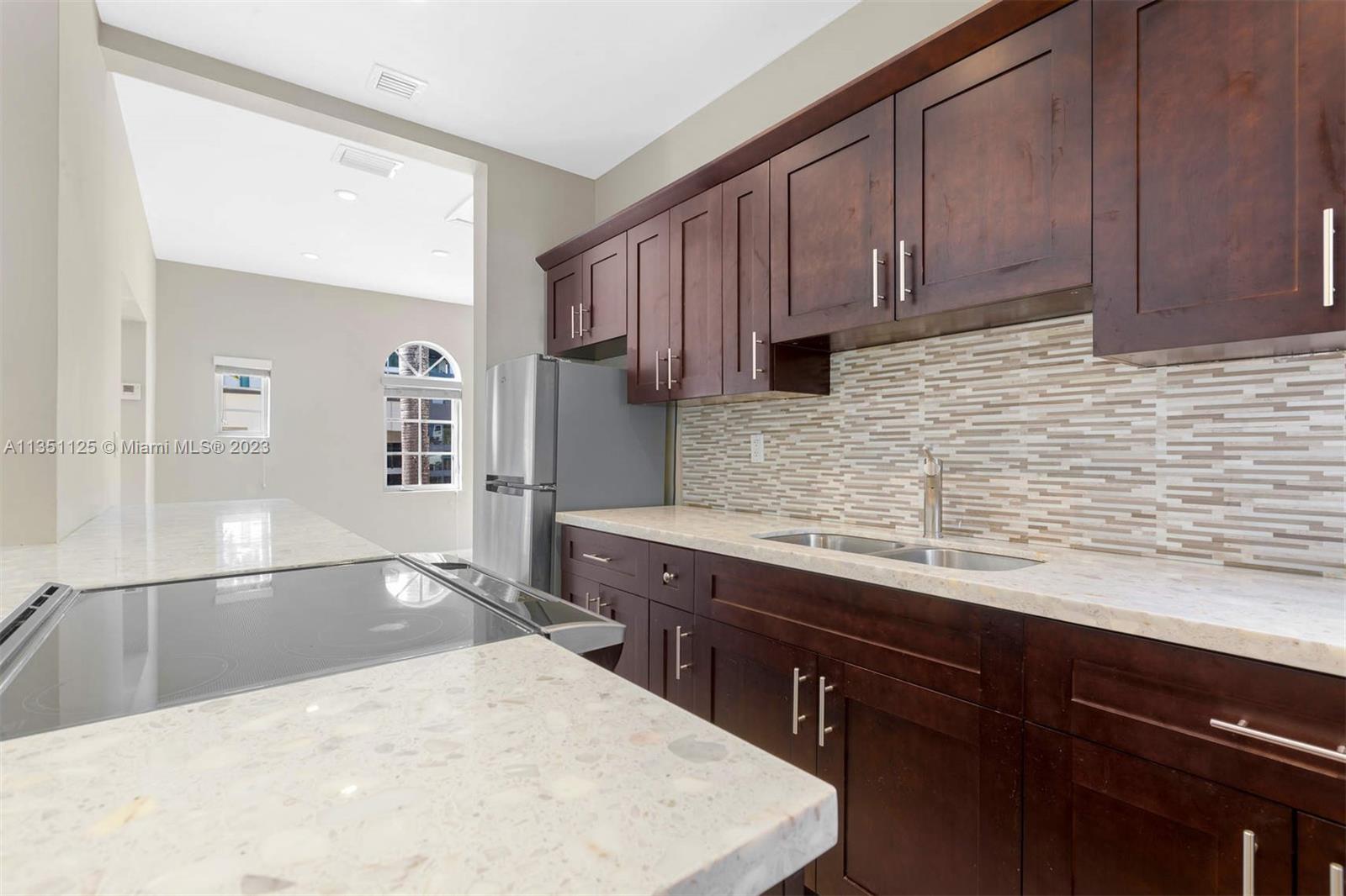 2423 Biscayne Boulevard, Unit 2 Miami, FL 33137 - Photo 3 of 14 a kitchen with stainless steel appliances wooden cabinets a sink and a stove