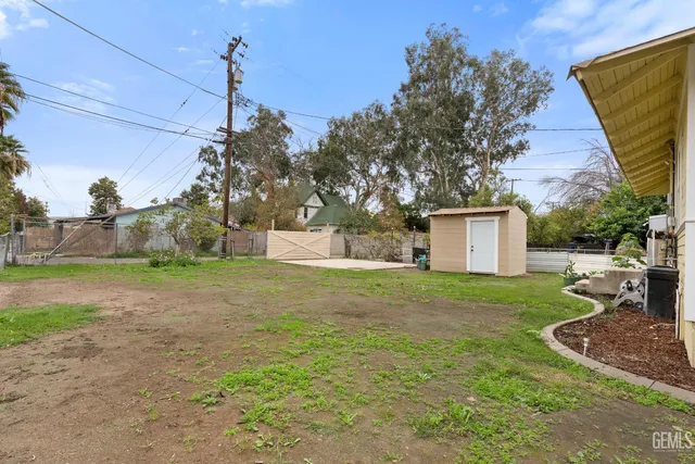 a backyard of a house with table and chairs plants and large tree