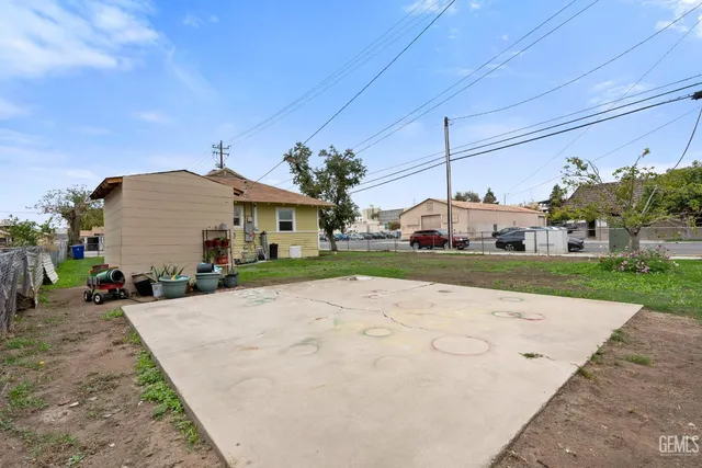 a view of a white house with a small yard and potted plants