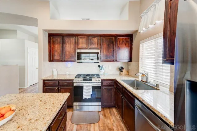 a kitchen with stainless steel appliances granite countertop a sink stove refrigerator and cabinets
