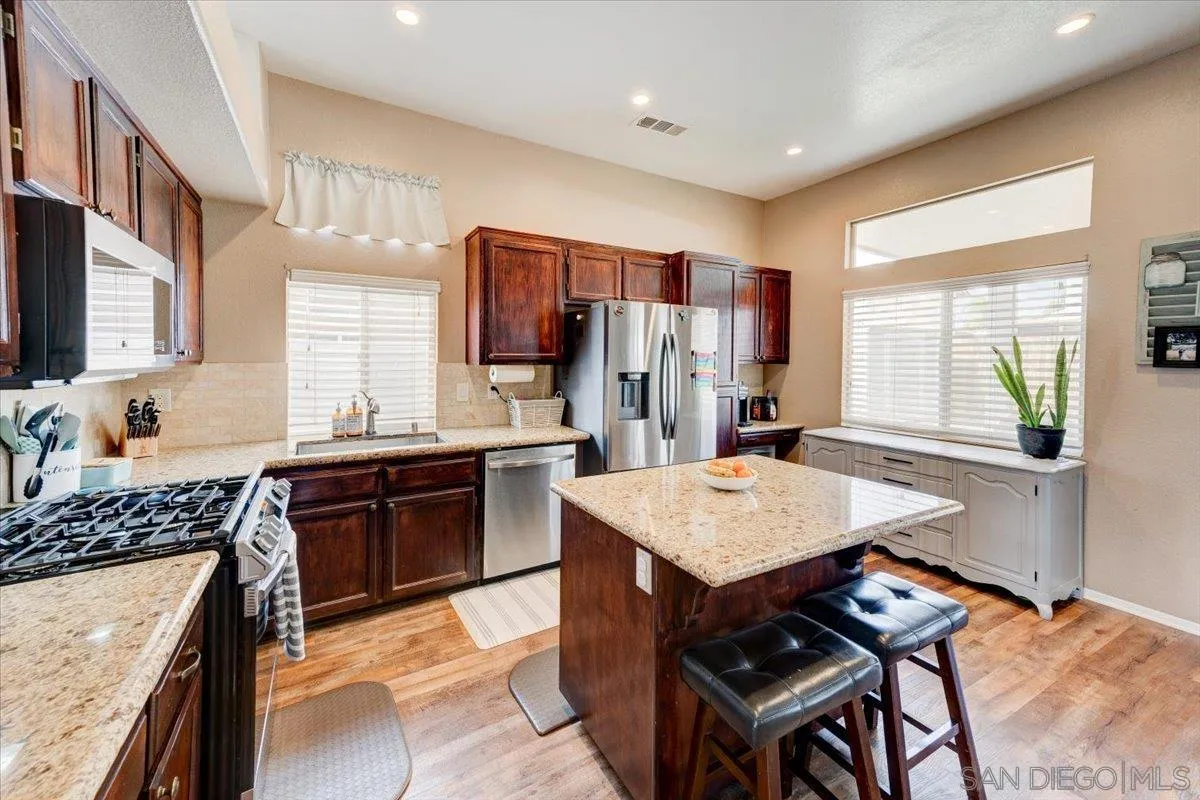 1359 H Street Ramona, CA 92065 - Photo 13 of 52 a kitchen with stainless steel appliances kitchen island granite countertop a stove refrigerator sink and cabinets