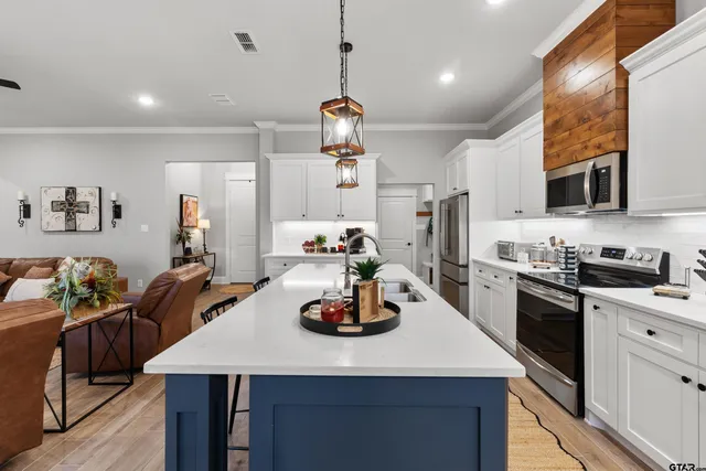 a kitchen with kitchen island granite countertop a sink cabinets and stainless steel appliances
