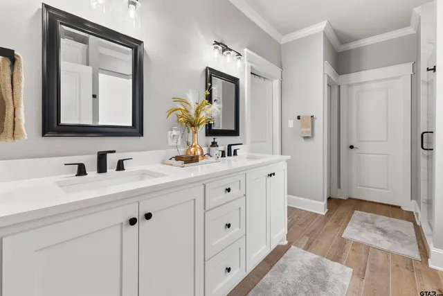 a spacious bathroom with double vanity a mirror and a shower