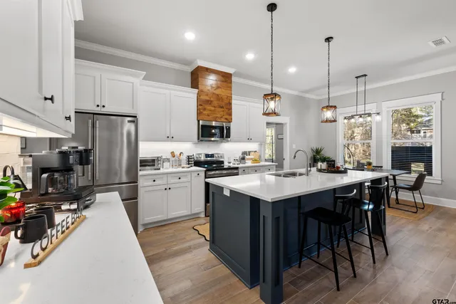 a kitchen with white cabinets appliances and wooden floor