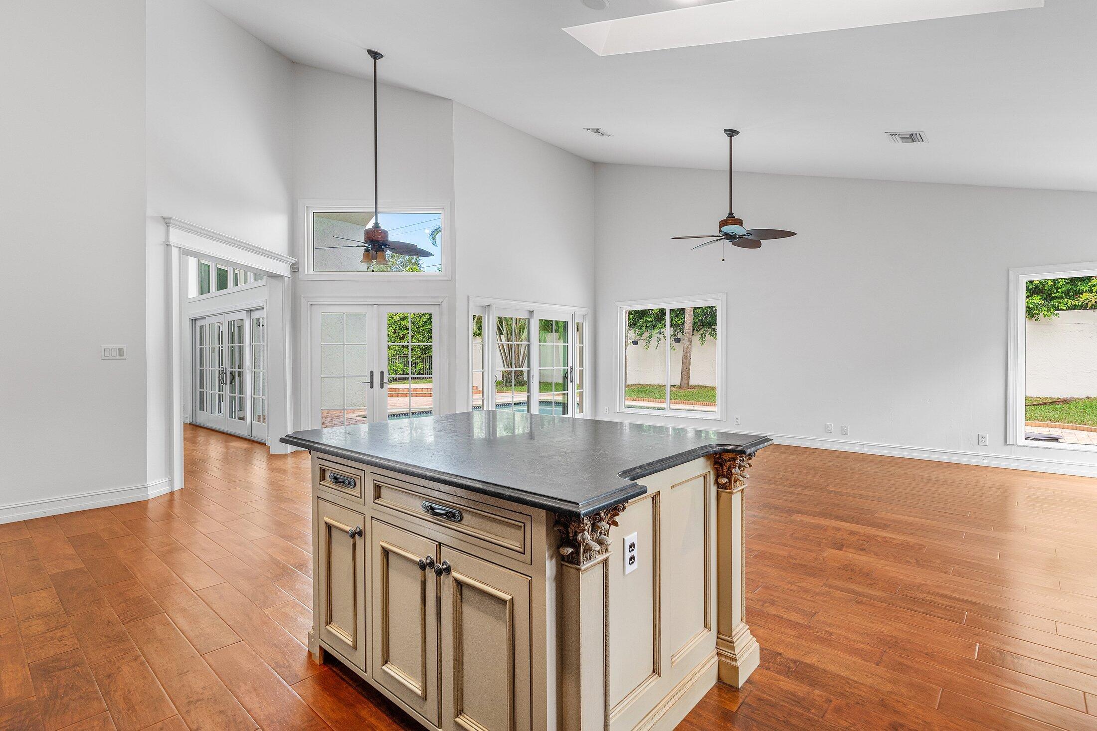 2599 Northwest 49th Street Boca Raton, FL 33434 - Photo 15 of 40 a kitchen with stainless steel appliances granite countertop a sink a stove a dining table and chairs with wooden floor