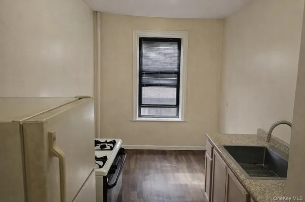 a kitchen with granite countertop a sink a stove and refrigerator